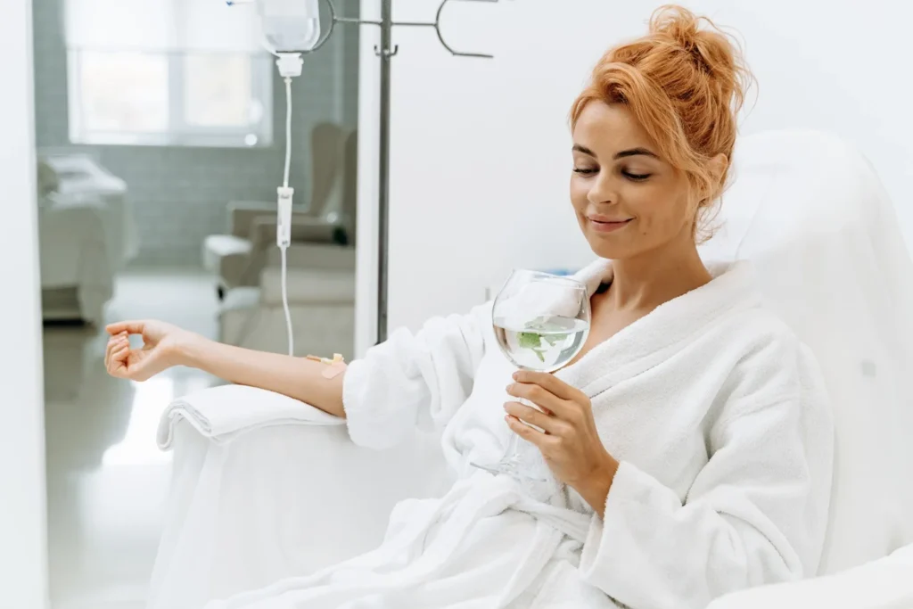 a woman in a white robe holding a glass of water